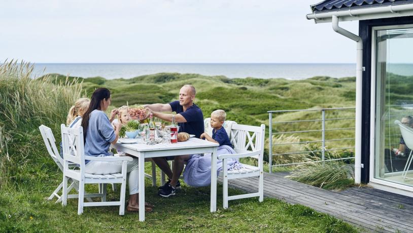 Famile ist Mittagessen auf der Terrasse eines Ferienhauses in Dänemark