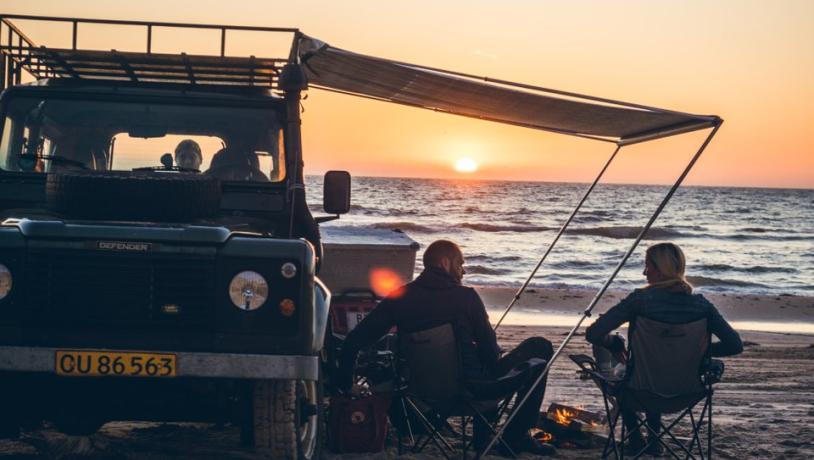 Twee kampeerders genieten van de zonsondergang op het strand bij Nørre Lyngby in Denemarken