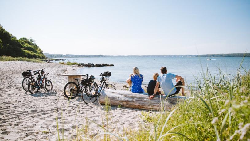 Een familie rust tijdens een fietsvakantie uit op het strand in Sønderjylland
