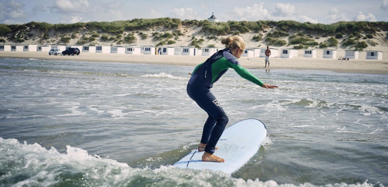Mädchen surft am Strand von Løkken im dänischen Nordjütland