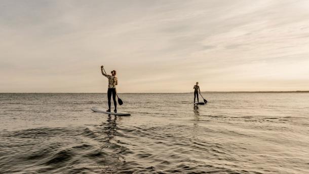 Two people go paddleboarding on a calm sea at Klitmøller, Thy National Park