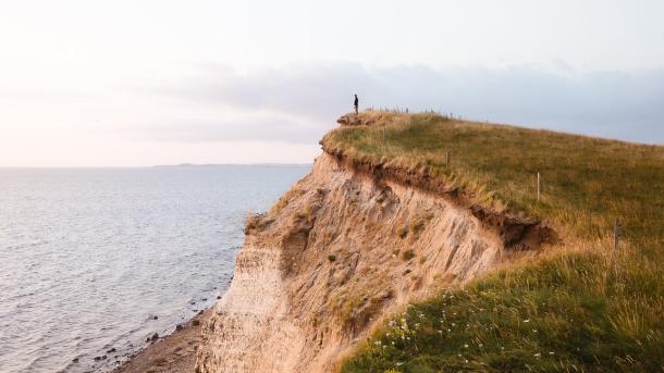 Person standing at the Limfjord on a cliff, Denmark
