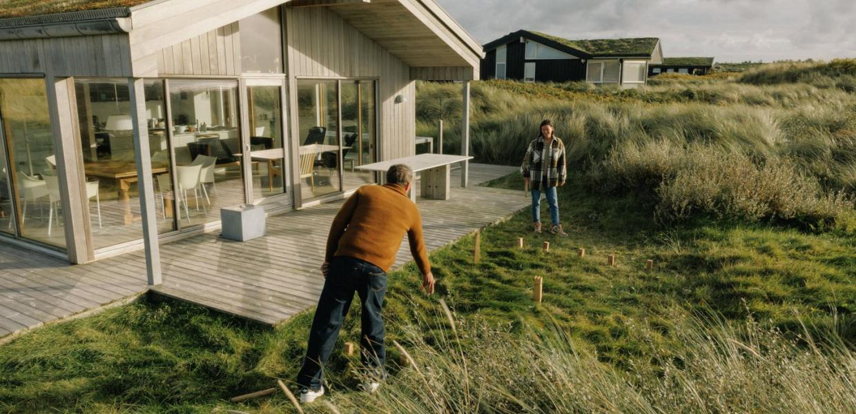 Paar spielt Wikingerschach am Ferienhaus an der dänischen Nordseeküste