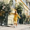 A girl in a yellow dress walks down a rose-lined Copenhagen street
