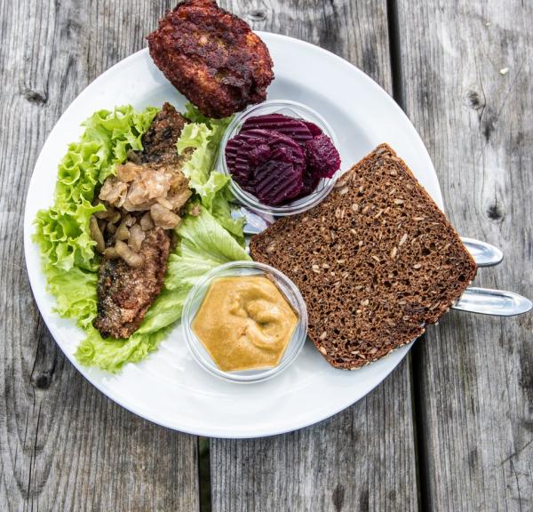 Tallerken med klassisk dansk smørrebrød med sild og frikadelle på et bord