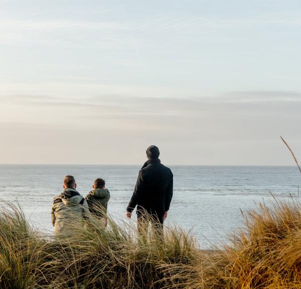 Familie kijkt naar de zee bij Blåvand strand, West-Jutland
