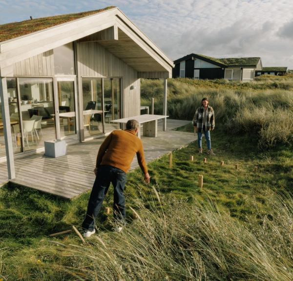 Paar spielt Wikingerschach am Ferienhaus an der dänischen Nordseeküste