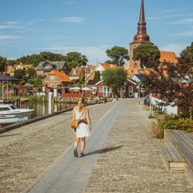 A woman walks beside the harbour in Nysted, Lolland Falster, Denmark